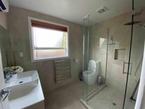 a bathroom with a sink and a toilet and a shower at Comfortable Home Close to Airport in Christchurch