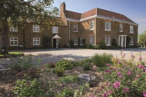 an old brick building with flowers in front of it at Kings Lynn Knights Hill Hotel & Spa, BW Signature Collection in King's Lynn