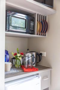 a kitchen counter with a microwave and some dishes at Sunrise suite in Collingwood