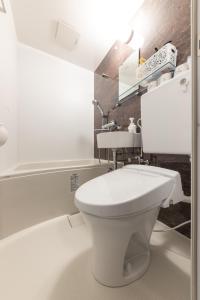 a bathroom with a white toilet and a sink at Kawasaki Station Inn in Kawasaki