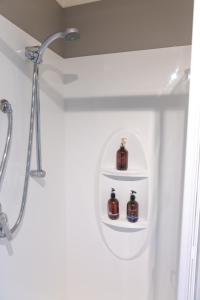 La salle de bains est pourvue d'une douche et de 2 bouteilles sur les étagères. dans l'établissement Sunrise suite, à Collingwood