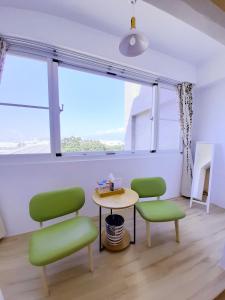 a room with two green chairs and a table and a window at Love Travel Guest House in Taitung City