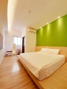 a bedroom with a large bed with a green wall at Love Travel Guest House in Taitung City +48 photos