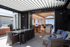 a patio with a table and chairs and a living room at Mountain Vista - beautifully renovated home with spa pool in Queenstown +20 photos