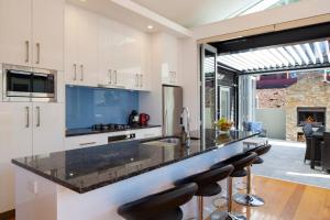 a kitchen with white cabinets and black counter tops at Mountain Vista - beautifully renovated home with spa pool in Queenstown