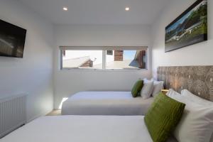 a white room with two beds and a tv at Mountain Vista - beautifully renovated home with spa pool in Queenstown