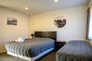 a bedroom with two beds and a clock on the wall at Foreshore Motor Lodge in Petone
