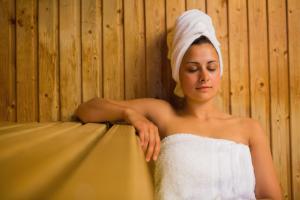 a woman with a towel on her head sitting on a couch at Waitakere Resort & Spa in Auckland
