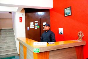 a man standing behind a counter in a red wall at Hotel Avlokan - Near Kainchi Dham Mandir in Bhowāli