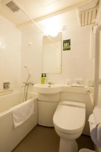 a white bathroom with a toilet and a sink at Kadoya Hotel in Tokyo