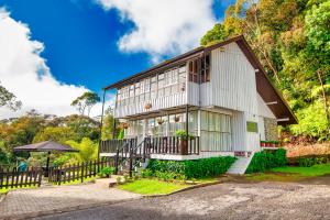 Ein weißes Haus mit einem Zaun daneben. in der Unterkunft Sutera Sanctuary Lodges At Kinabalu Park in Kampong Kundassan