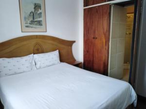 Schlafzimmer mit einem weißen Bett mit einem Kopfteil aus Holz in der Unterkunft Johannesburg Youth Hostel in Johannesburg