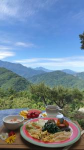 Margaret Garden Villa في ريناي: طبق من الطعام على طاولة مع جبال في الخلفية