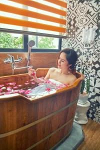eine Frau in einer hölzernen Badewanne mit Waschbecken in der Unterkunft Entire Cosy Apartments May Homestay Hanoi in Hanoi