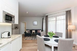 een keuken en een woonkamer met een witte tafel en stoelen bij Vanilla Rentyear Apartments in Gdańsk