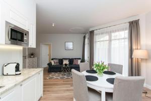 a kitchen and living room with a white table and chairs at Vanilla Rentyear Apartments in Gdańsk
