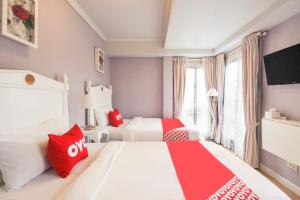 um quarto com 2 camas com almofadas vermelhas e brancas em OYO 899 Villa De Hun em Chiang Mai