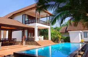 a villa with a swimming pool in front of a house at Vuon Xoai Resort in Ấp Phước Cang