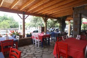 un restaurant avec des tables et des chaises rouges et un toit en bois dans l'établissement Yeni Bademli Konuk Evi, à Gokceada Town