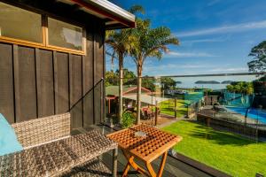 uma varanda com uma mesa e vista para um quintal em Anglers Lodge em Coromandel Town