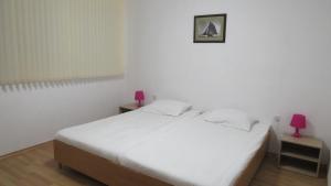 um quarto com uma cama branca e 2 candeeiros cor-de-rosa em Apartment Crystal em Balchik