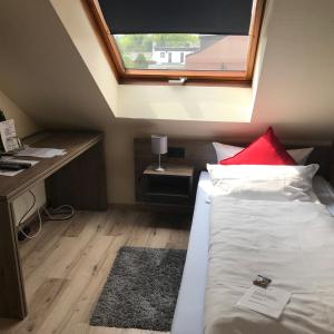 a bedroom with a bed with a window and a desk at Hotel Rahserhof in Viersen