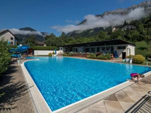 a person is standing next to a large swimming pool at MAYER - Wirtshaus und Dorfhotel in Sankt Martin am Grimming