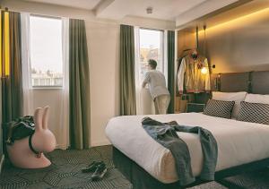 un homme qui regarde par la fenêtre d'une chambre d'hôtel dans l'établissement Assembly Leicester Square, à Londres