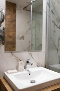 La salle de bains est pourvue d'un lavabo blanc et d'un miroir. dans l'établissement Mila Apartment & SPA, à Zlatibor