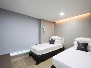 a room with two beds with white sheets and pillows at K-Grand Hostel Gangnam1 in Seoul
