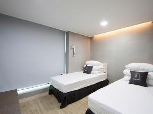 a room with two beds with white sheets and pillows at K-Grand Hostel Gangnam1 in Seoul +85 photos