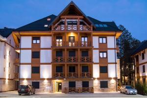 a large building with cars parked in front of it at Tenea Apartment & SPA in Zlatibor