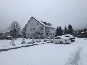 zwei Autos im Schnee vor einem Haus geparkt in der Unterkunft Mini Hotel Furmi in Schidnyzja