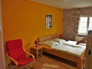 1 dormitorio con 1 cama y 1 silla roja en Bed And Breakfast Isidorus, en Winterberg