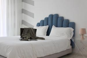 a large bed with a blue headboard and white pillows at S'O Suites Tropea in Tropea