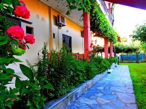 a house with red flowers and a walkway at Anastasia Chalatsogianni Rooms in Paralia Panteleimonos