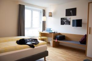 a bedroom with a bed and a desk and a window at Dialoghotel Eckstein in Zug