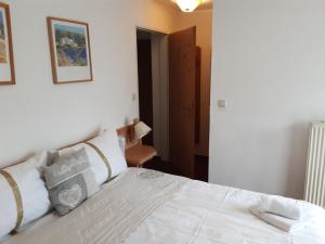 Schlafzimmer mit einem Bett mit weißer Bettwäsche und Kissen in der Unterkunft Apartment House Seerose in Obertraun