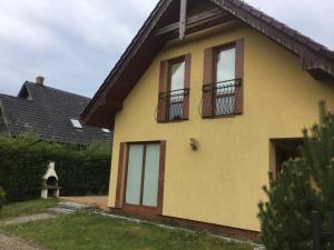 żółty dom z 2 oknami i balkonem w obiekcie Dom Koral Poddabie w Poddąbiu +11 zdjęć