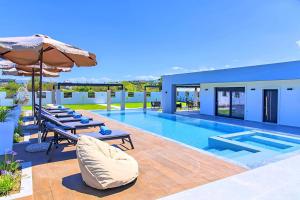 a swimming pool with chairs and an umbrella at Villa Solaris Heated Pool & Jacuzzi in Georgioupolis