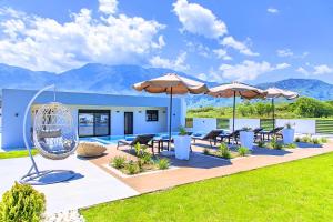 patio z krzesłami i parasolami na dziedzińcu w obiekcie Villa Solaris Heated Pool & Jacuzzi w mieście Georgioupolis