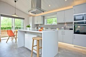 a kitchen with white cabinets and a bar with stools at Orchard Lodge, Strawberryfield Park in Cheddar