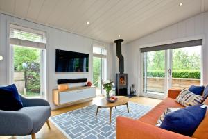 a living room with a couch and a tv at Orchard Lodge, Strawberryfield Park in Cheddar