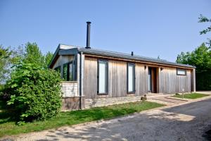 ein Haus mit einer Holzfassade mit einer Auffahrt in der Unterkunft Orchard Lodge, Strawberryfield Park in Cheddar