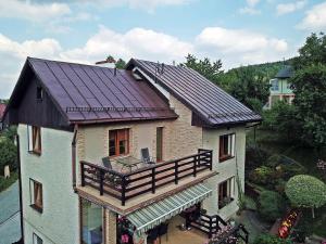 een huis met een dak, een veranda en een balkon bij Dom na wzgórzu in Duszniki Zdrój