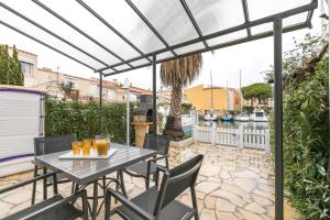 un patio con mesa, sillas y una valla en Calypso, en Cap d'Agde