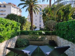 a patio with a table and chairs and palm trees at Hôtel de Provence in Cannes
