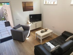 uma sala de estar com um sofá, uma televisão e uma mesa em Bosweg 9a, Comfortabele vakantiewoning, Centrum Zoutelande em Zoutelande