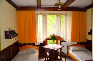 a bedroom with two beds and a table and a window at Ośrodek Wypoczynkowo-Szkoleniowy HALNY in Zawoja