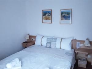 オーバートラウンにあるアパートメント ハウス ゼーローゼの白いベッド1台、壁に2枚の写真が飾られたベッドルーム1室